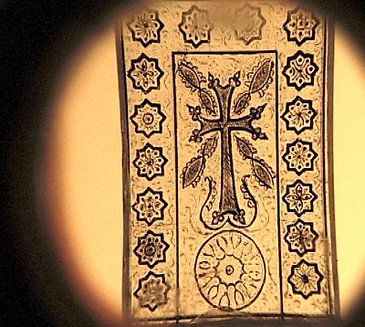 Другой хачкар, выгравированный на янтарной поверхности, сопровождаемый армянскими народными орнаментами.