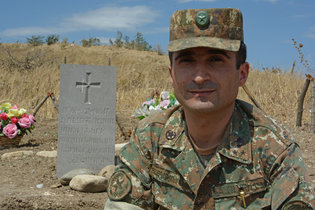 Капитан Гегам Григорян возле могилы солдата, который был похоронен недалеко от окопов весной этого года в Нагорном Карабахе. 